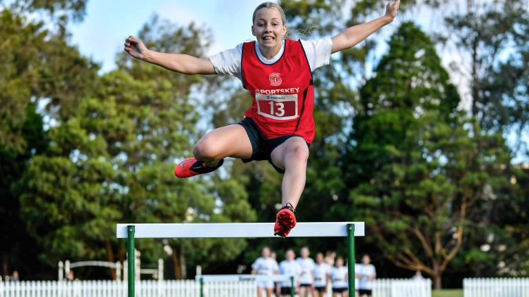 Sportskey female athlete jumping over hurdles